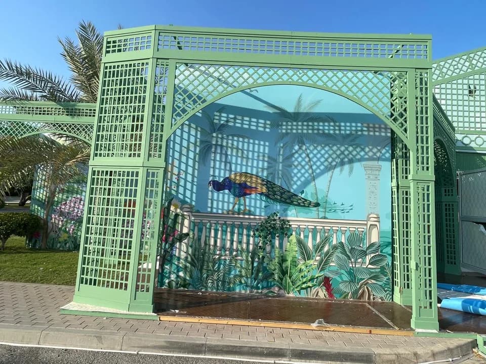 Custom outdoor lattice pavilion structure with hand-painted mural backdrop