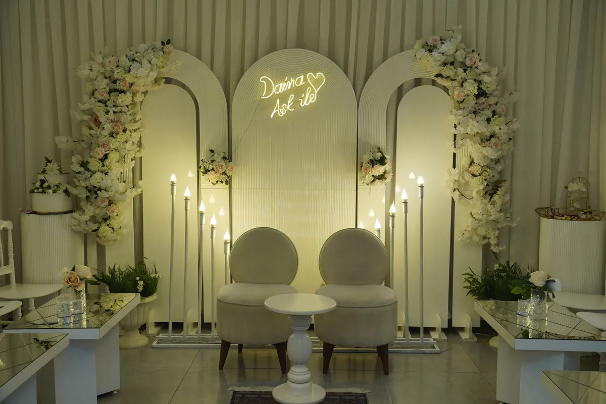 Elegant wedding stage backdrop with white arches neon sign and floral decor Saudi Arabia